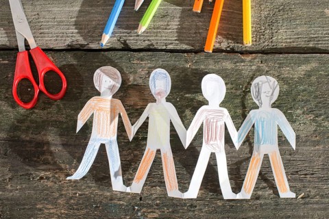 Paper made people figures. Painted white figures on wooden board