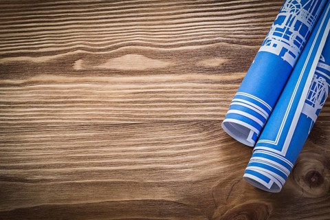 Blue rolled construction plans on wooden board copy space