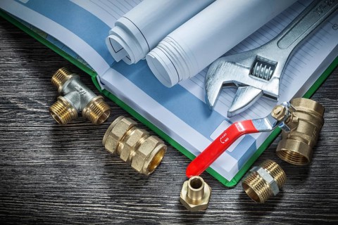 Adjustable spanner plumbing pipe connectors rolled blueprints water valve notebook pen