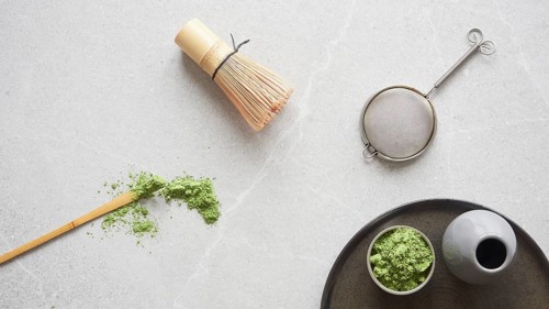 Matcha green tea powder and utensils for drink preparation: traditional bamboo spoon and whisk. Top