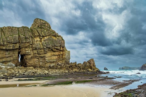 Noon on the beach of Playa di Arnia, Spain. Rocky picturesque ocean coast. Cantabria. Windy stormy
