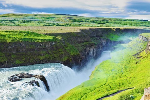 Grandiose Gullfoss in Iceland. In July raging water is shined with the bright morning sun. River