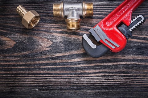 Monkey wrench brass equal tee hose nipple on wooden background plumbing concept