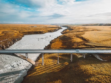 Bright blue river under the bridge trough Iceland mainland in autumn time on a cold day.