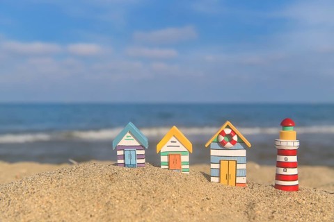 Miniature wooden huts and lighthouse at the beach