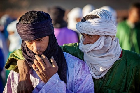 Two men in traditional dress and turbans, one puts his arm around the other, The traditional Tuareg