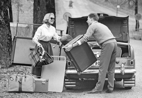 Couple in the 1950s. A young couple are packing the trunk of their car with luggage and camping