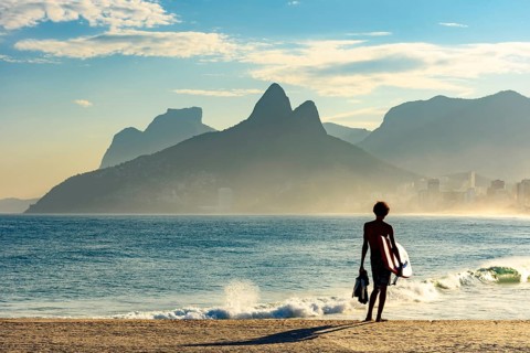 Young bodyboarder looking at the sea and Ipanema beach during a sunny afternoon