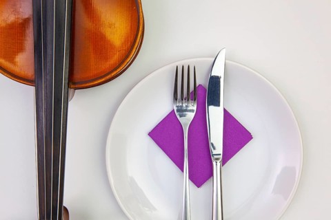 Symphony of taste. White plate and old violin on the white wooden table.Top view. Flat Lay Image
