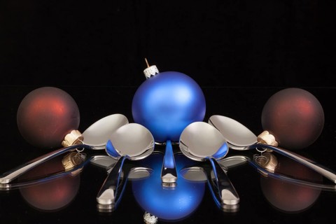 Blue Christmas decoration and five spoons on a black glass desk