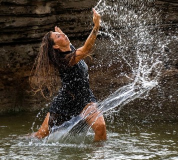 Middle-aged woman dancing and throwing water in the air, Maioris beach, llucmajor, Majorca,