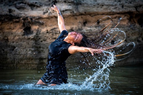 Middle-aged woman dancing and throwing water in the air, Maioris beach, llucmajor, Majorca,