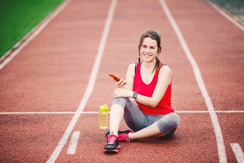 Beautiful fitneß girl uses smartphone at stadium after workout. Sports and healthy. Sport woman use