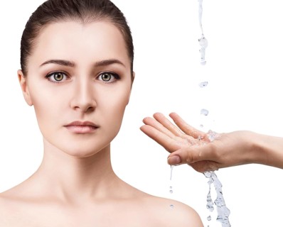 Beautiful woman face and splashes of water in hands. Cleansing and moisturizing concept