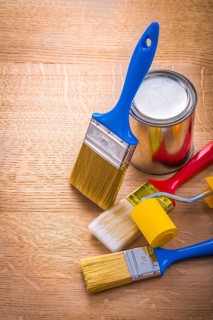 Set of paint brushes roller and can on wooden board