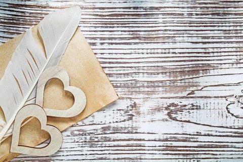 Old paper sheet plume wooden hearts on vintage wood board celebrations concept
