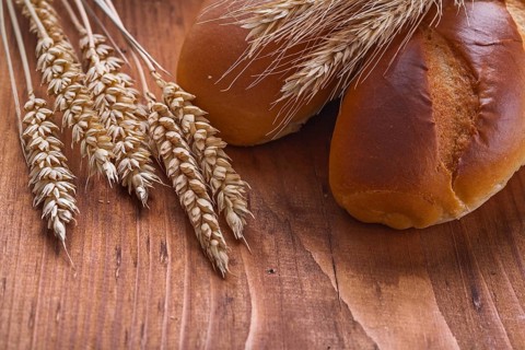 Bread with wheat ears on old wooden board