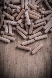 Variety of cylinder wooden dowel pins on wood board construction concept
