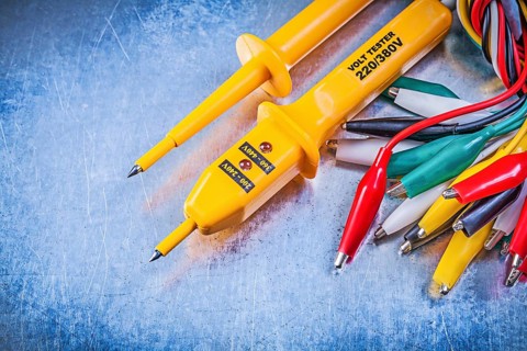 Yellow electrical tester set of multicolored crocodile clip cables on metallic background