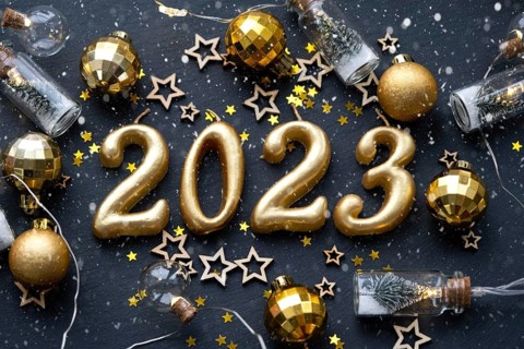 The golden figures 2023 made of candles on a black stone slate background are decorated with a