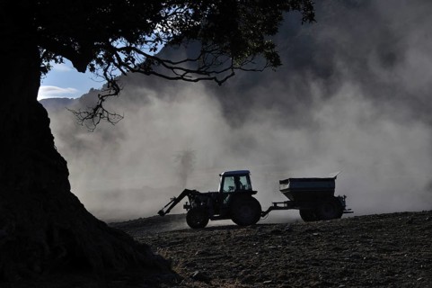 Tractor spreading lime with a fertiliser spreader, West Coast, New Zealand, Oceania