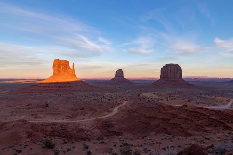 A picture of the Monument Valley landscape at sunset, with the West Mitten Butte, East Mitten Butte