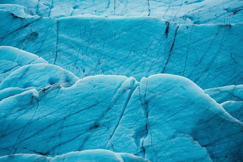 Detailed close-up of a glacier's textured surface with deep blue tones, iceberg, glacier, snow, ice