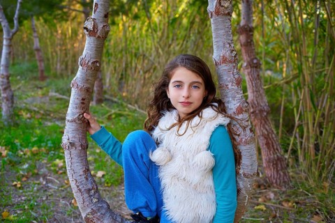 Autumn kid girl relaxed in forest with green canes background