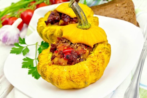 Two yellow squash stuffed with meat, tomatoes and peppers in the dish, bread, garlic, parsley and a