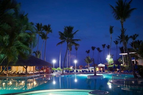 Tropical resort at night. View with empty restautant, huge palms and electric lights reflecting in
