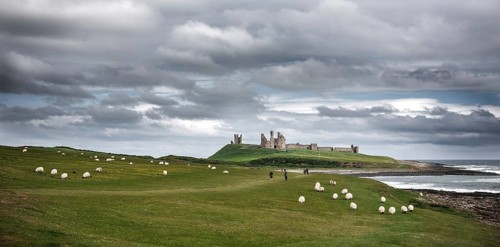 The ruins of Dunstanburgh Castle as seen from Craster along the shoreline of The North Sea,
