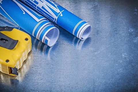 Blue construction drawings measuring tape on metallic background maintenance concept