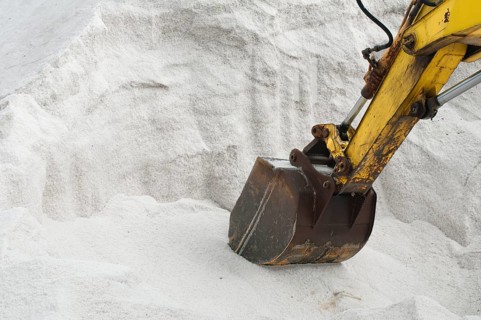 Excavator digging pile white salt