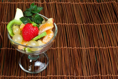 Fruit salad in a glass bowl on wooden base