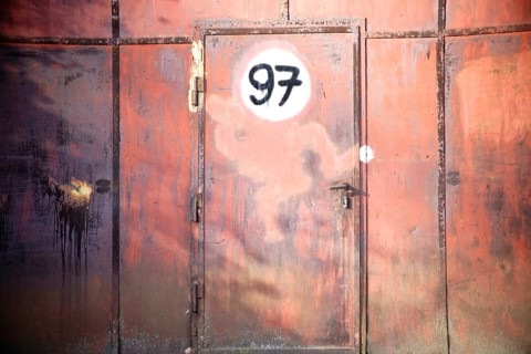 A rusty iron gate with a door and a painted sign