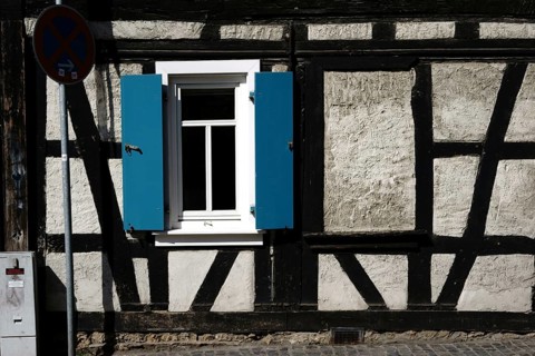 An old rickety half-timbered house with a striking beam construction and shutters at the window