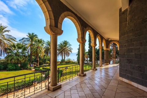 The basilica is surrounded by gallery with columns. Subtle shade of palms. Church Sermon on the