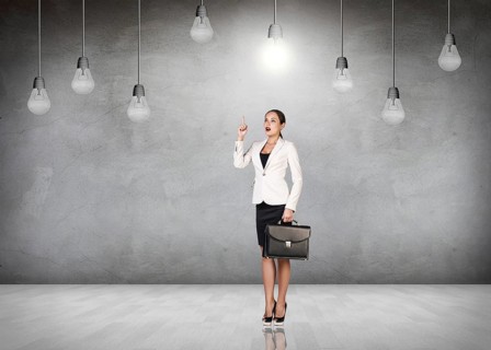 Business woman stands in a gray room with hanging bulbs
