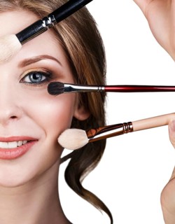 Many hands with cosmetics brushes applying make-up to glamour woman, over white background