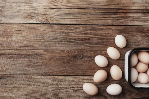 Organic chicken eggs in metal box on wooden background in a row. Organic household concept with