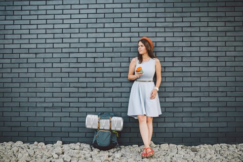 Cheerful girl in dress holding take away cup. Hipster model wearing stylish summer outfit Outdoors.