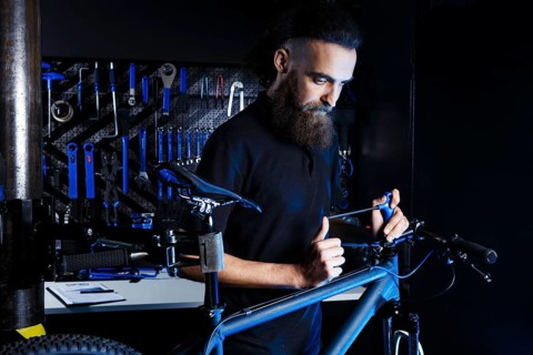 Theme sale and repair of bicycles. Young and stylish with a beard and long hair, a Caucasian man