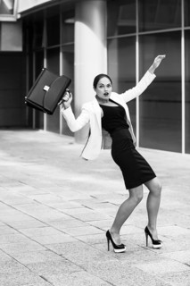 Scared young businesswoman with briefcase and gesturing fear on city background