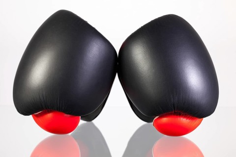 Red and black boxing gloves on a glass table isolated on white background
