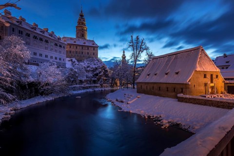 Winter view of Cesky Krumlov, picturesque houses under the castle with snow-covered roofs. Narrow