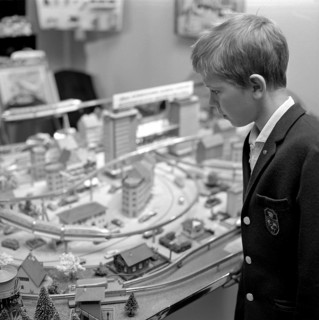 Toys in the 1960s. A boy at a model railway in a store. It's built with buildings and trees and was