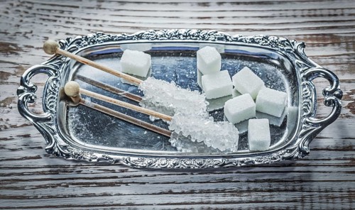 White sugar cubes sticks tray on vintage wooden board