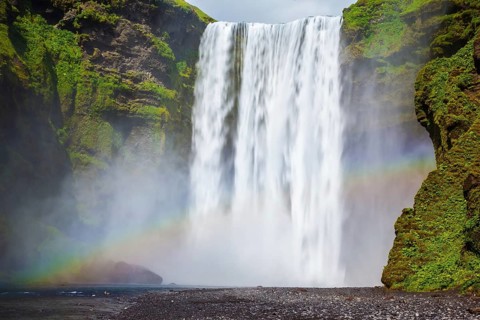 Picturesque rainbow appears in the water mist. The most popular waterfall in Iceland - Skogafoss.