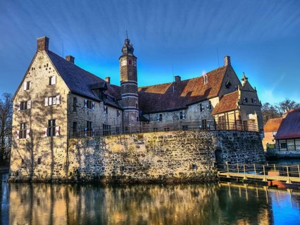 Medieval castle with a moat, shining in the sunlight against a blue sky, Lüdinghausen, münsterland,