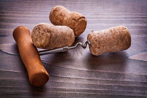 Classical corkscrew and corks of champagne on vintage wooden board alcohol concept